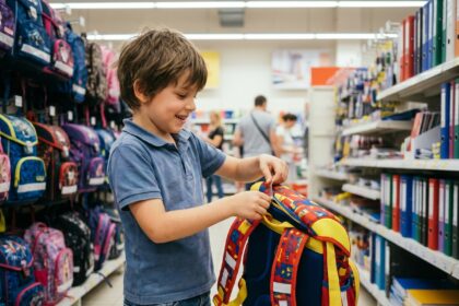 Garçon souriant avec sac à dos coloré en magasin